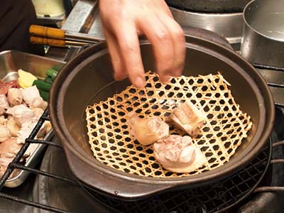 取り出した肉は、ていねいに水洗いしておく。再び鍋に網を敷き、その上に洗った肉と金華ハム、アワビを並べていく。
