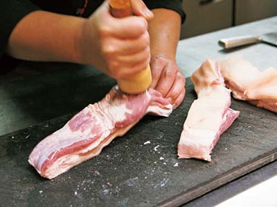 フォークや剣山のようなもので、豚肉の表面をまんべんなく刺す。皮目もしっかりと刺したら、1.5～２％の塩（煎った塩に山椒の粒を少し混ぜたもの）をふる。身の厚い部分には多めの塩を。