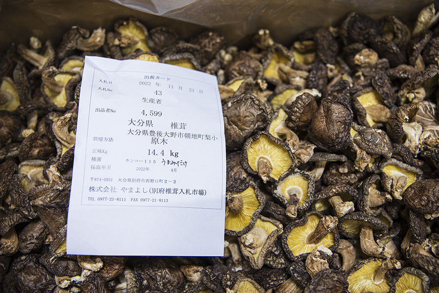 競りで取引される椎茸には紙に書かれた生産者情報が付けられている。購入者は値段を書いた紙を入札する。